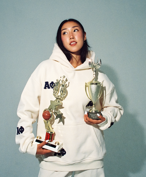 Person wearing a cream hoodie with navy greek letter patches
